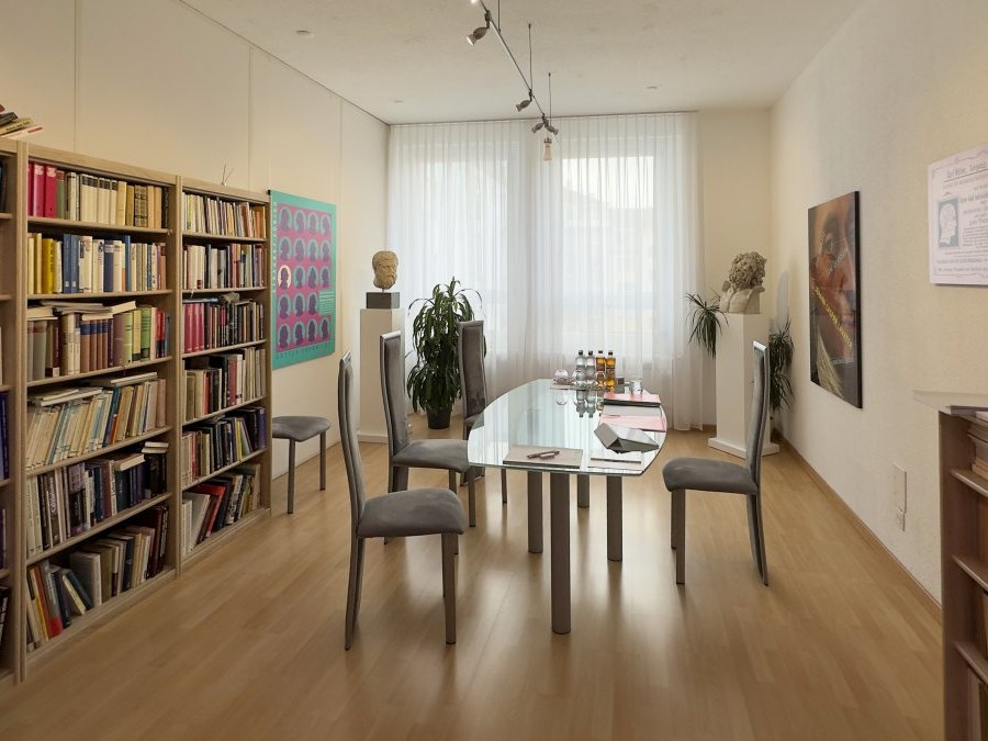 Eines der Beratungszimmer des Carl-Huter-Instituts, mit Tisch, Stühlen und Bücherwand
